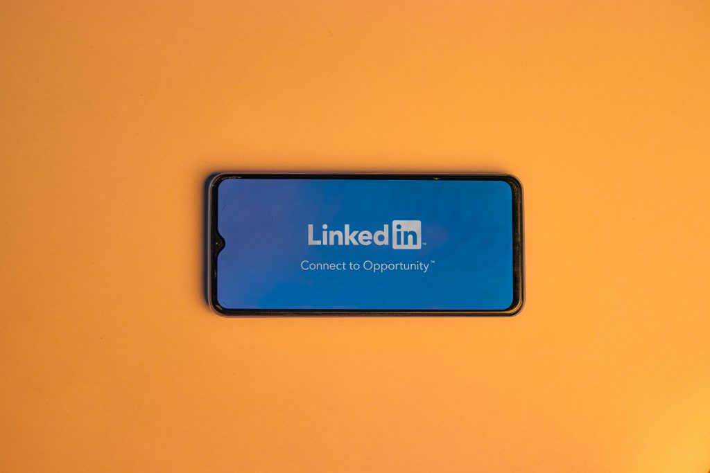 Smartphone showing LinkedIn login on vibrant orange background, symbolizing connectivity.